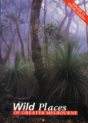 The cover image of Wild Places of Greater Melbourne, featuring a view of misty bush land, with spiky short green plants next to tall gum trees.