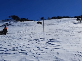 Photo of hillside snow course in the Australian Alps with distant small trees and an onlooker