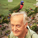 Photograph of Roger Tory Peterson with a Rainbow Lorikeet perched on his head.