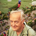 Photograph of Roger Tory Peterson with a Rainbow Lorikeet perched on his head.